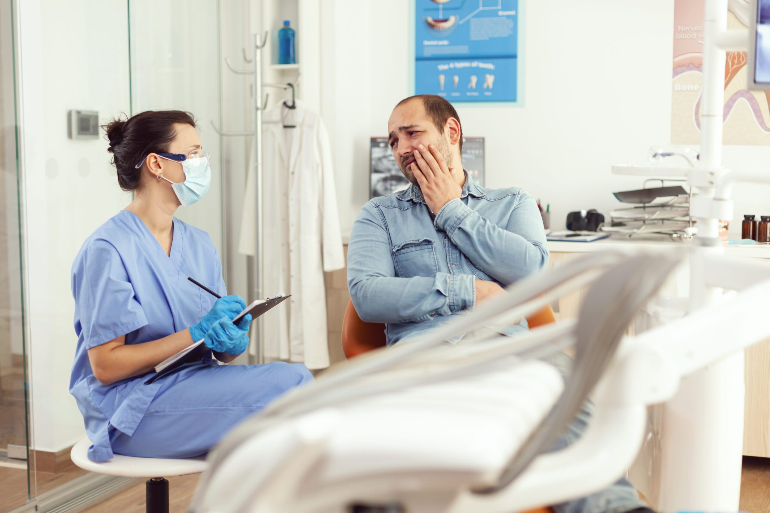 Dental assistant writing stomatology treatment on clipboard in dental clinic